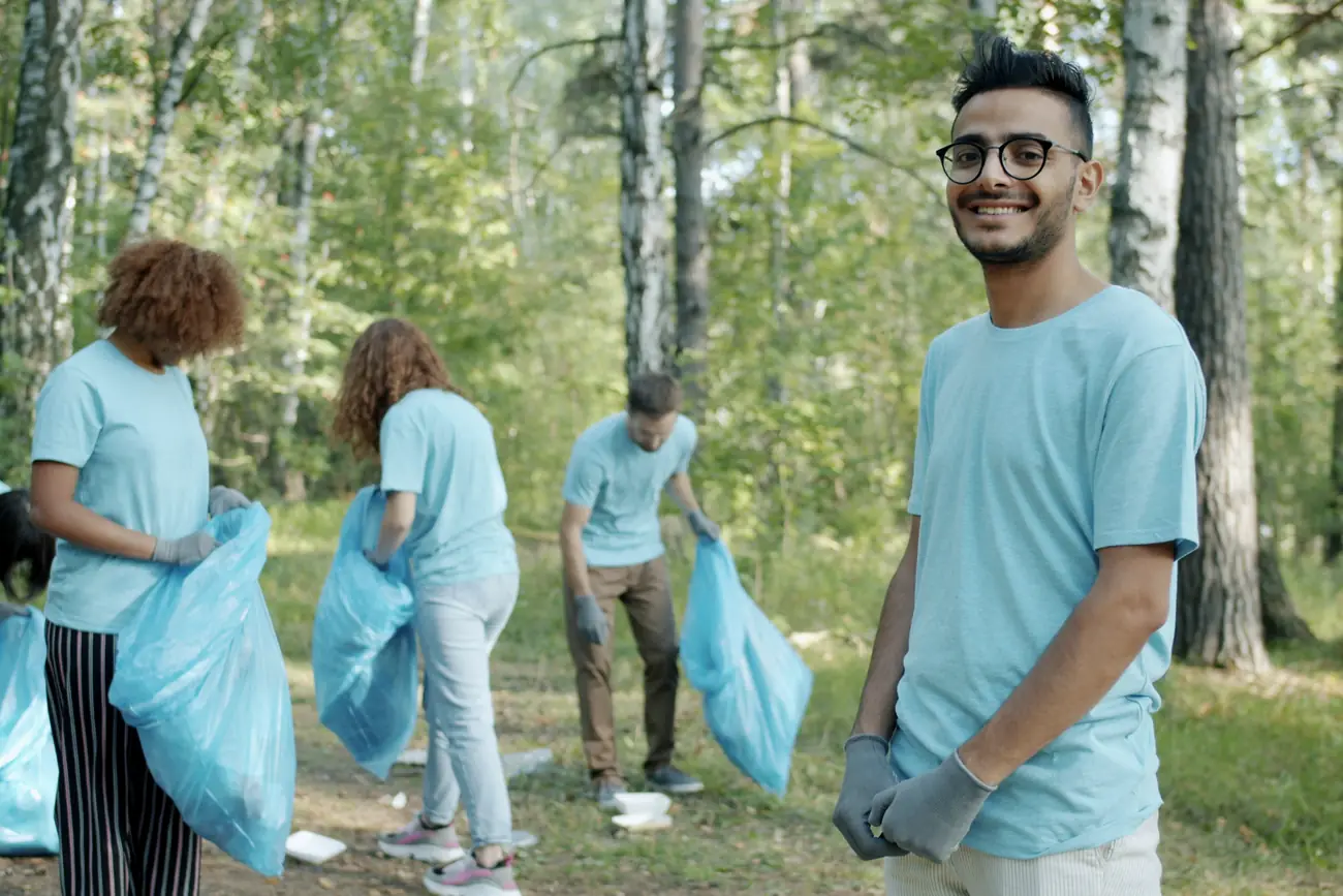 A volunteer with his team clearing litter from woodland